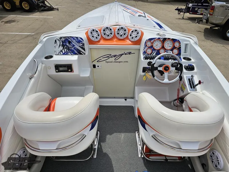 Slide: The Image of 2005 Baja 25 Outlaw boat interior with white seats, vibrant dashboard, and steering wheel. - 49