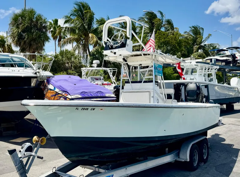The Image of 1963 Bertram 25 Mark II sport cruiser on trailer, surrounded by palm trees and other boats. - 0