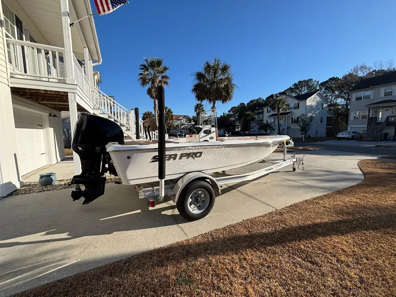 Slide: The Image of 2023 Sea Pro 172 Bay boat on trailer, parked in residential area with palm trees. - 11
