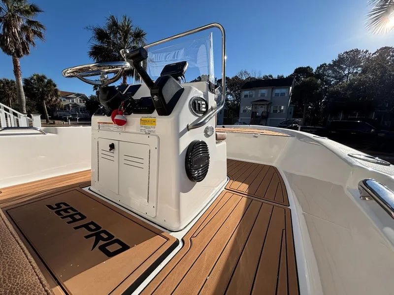 Slide: The Image of 2023 Sea Pro 172 Bay boat with sleek console and wood-style deck, under clear blue sky. - 15