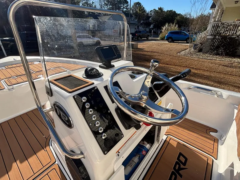Slide: The Image of 2023 Sea Pro 172 Bay boat dashboard with steering wheel and controls, parked outdoors. - 19