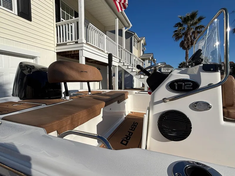 Slide: The Image of 2023 Sea Pro 172 Bay boat docked near coastal homes under clear blue sky. - 6