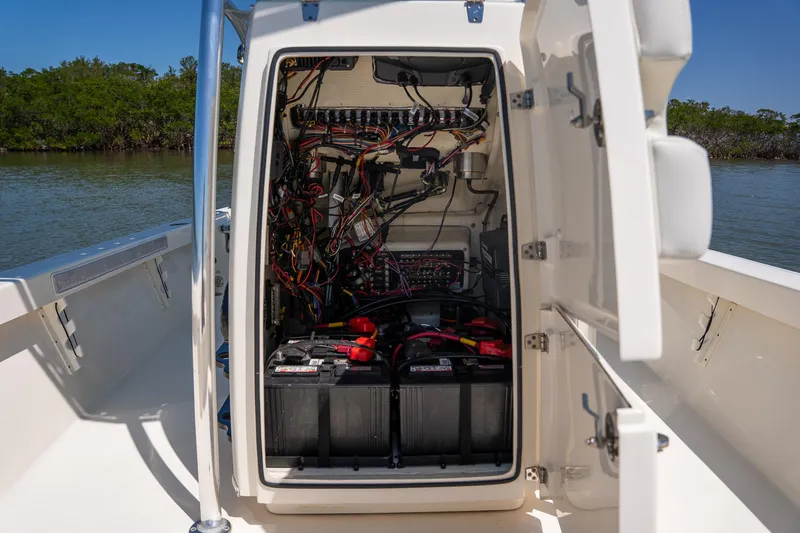 Slide: The Image of 2018 Pathfinder 2400 TRS boat electrical compartment with batteries and wiring, open on a sunny day. - 39