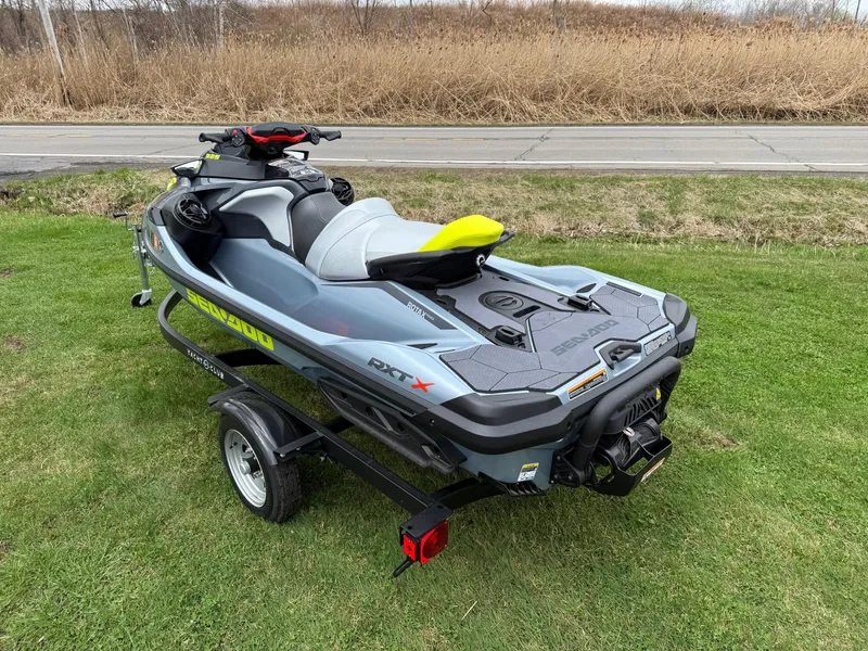 Slide: The Image of 2024 Sea-Doo RXT-X 325 in Ice Metal/Manta Green on trailer, parked on grass. - 6