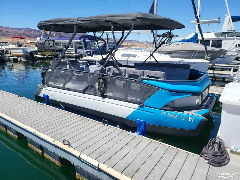 Slide: The Image of 2023 Sea-Doo Switch Cruise 21 pontoon boat docked at a marina. - 11