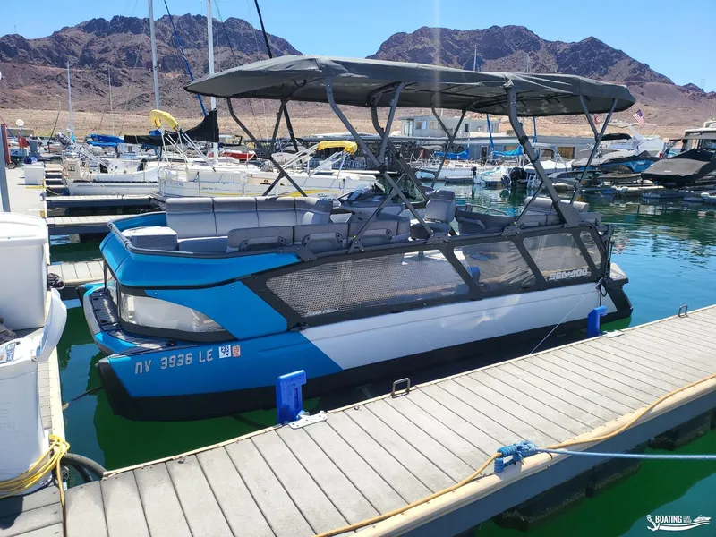 Slide: The Image of 2023 Sea-Doo Switch Cruise 21 docked at marina with mountainous backdrop. - 12