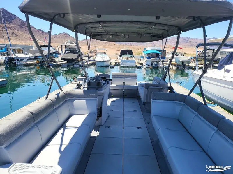Slide: The Image of 2023 Sea-Doo Switch Cruise 21 pontoon boat docked at a marina with scenic mountain views. - 13