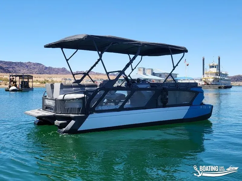 Slide: The Image of 2023 Sea-Doo Switch Cruise 21 pontoon boat on a calm lake with scenic background. - 4