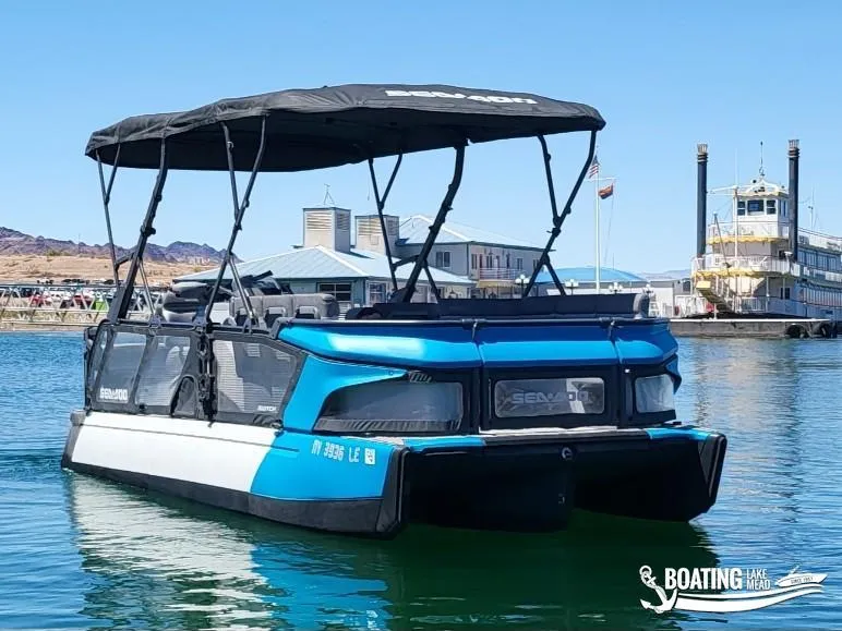 Slide: The Image of 2023 Sea-Doo Switch Cruise 21 pontoon boat on calm water near a dock. - 5