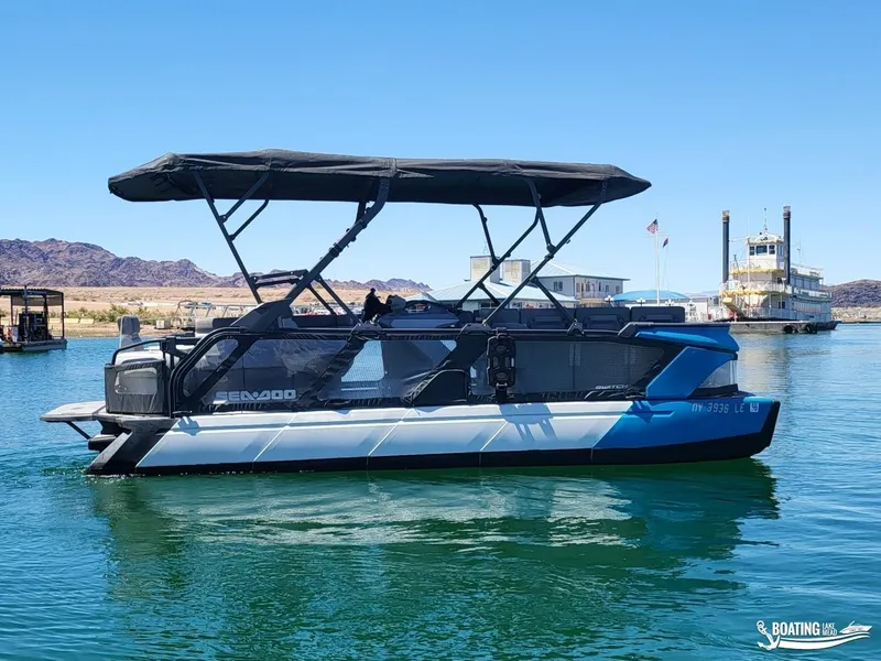 Slide: The Image of 2023 Sea-Doo Switch Cruise 21 pontoon boat on a serene lake with distant mountains. - 6
