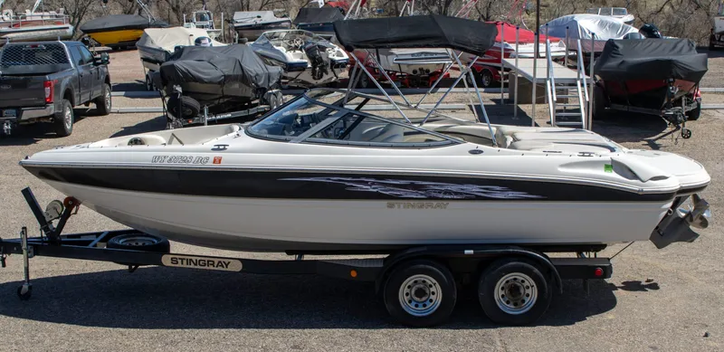 Slide: The Image of 2013 Stingray 225 LR boat on trailer in a marina parking lot. - 1