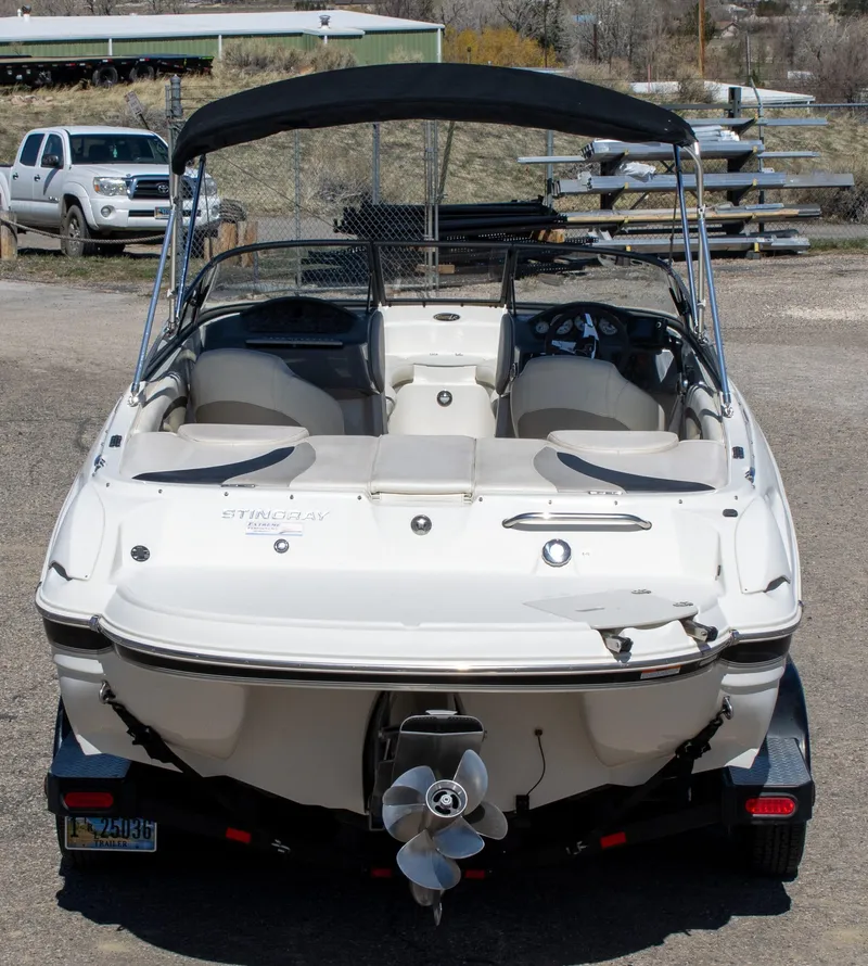 Slide: The Image of 2013 Stingray 225 LR boat with canopy, parked on a trailer in a yard. - 4