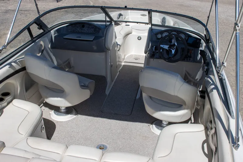 Slide: The Image of 2013 Stingray 225 LR boat interior with beige seating and steering console. - 9