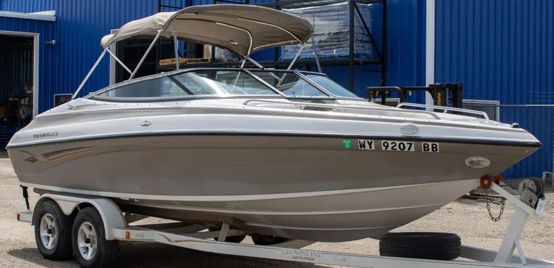 Slide: The Image of 2003 Crownline 225 BR boat on trailer, parked near blue building. - 1