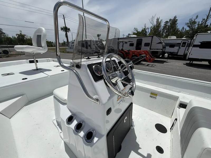 Slide: The Image of 2025 G3 Bay 20 boat interior with steering console and seating, parked near RVs. - 5