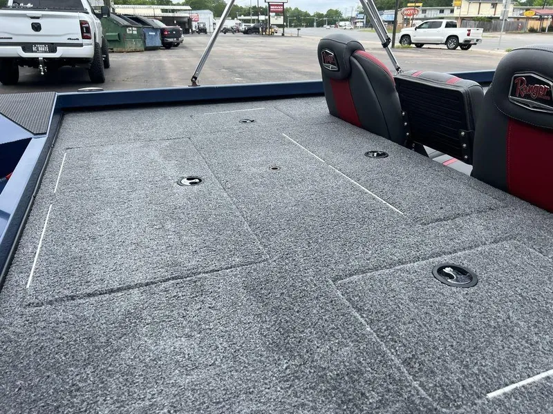 Slide: The Image of 2022 Ranger RT178C boat interior with gray carpet and red-accented seats in a parking lot. - 40