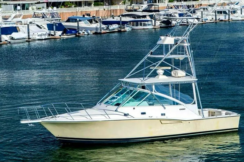 The Image of 1998 Cabo 35 Express yacht docked in a marina, surrounded by other boats. - 1