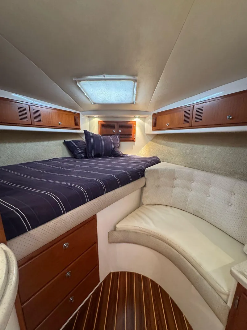 Slide: The Image of 1998 Cabo 35 Express cabin with bed, seating, and wooden cabinetry. - 15