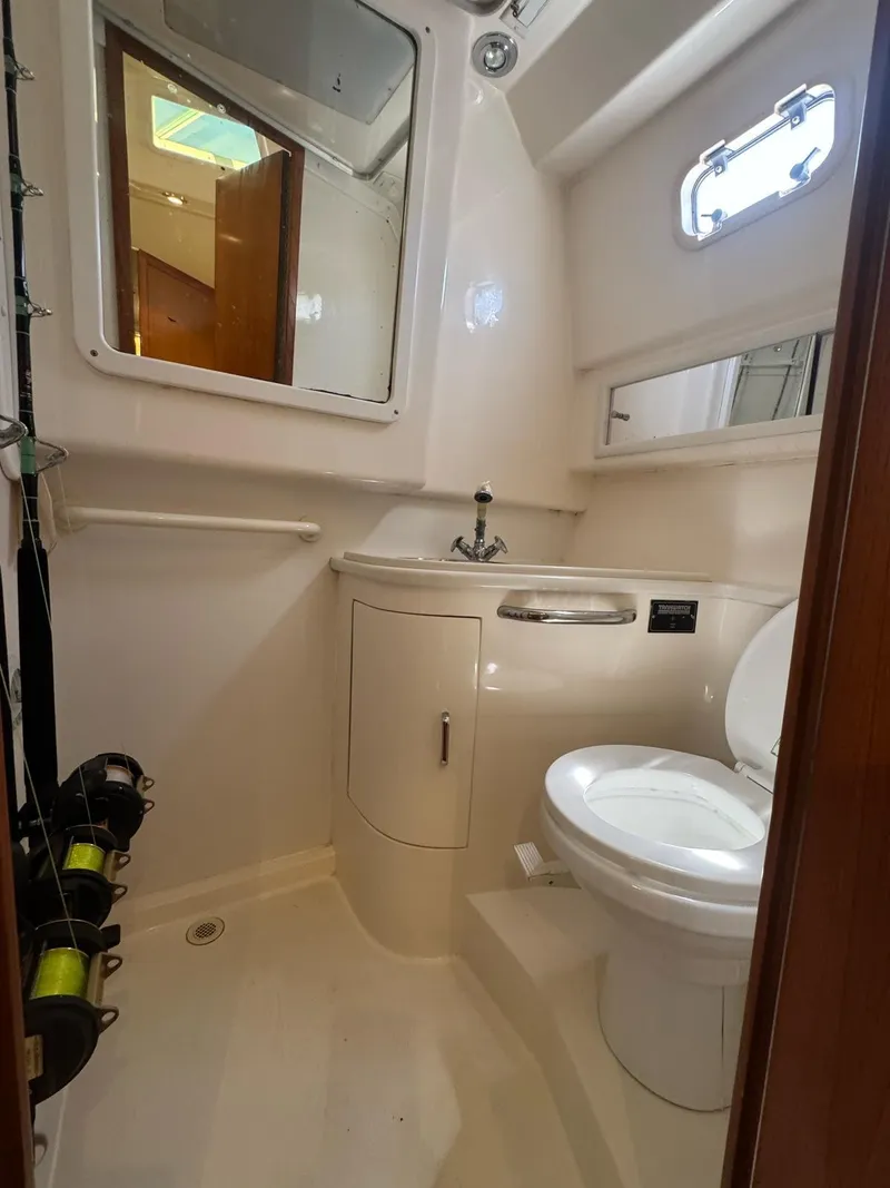 Slide: The Image of 1998 Cabo 35 Express boat bathroom with toilet, sink, and fishing rods. - 17