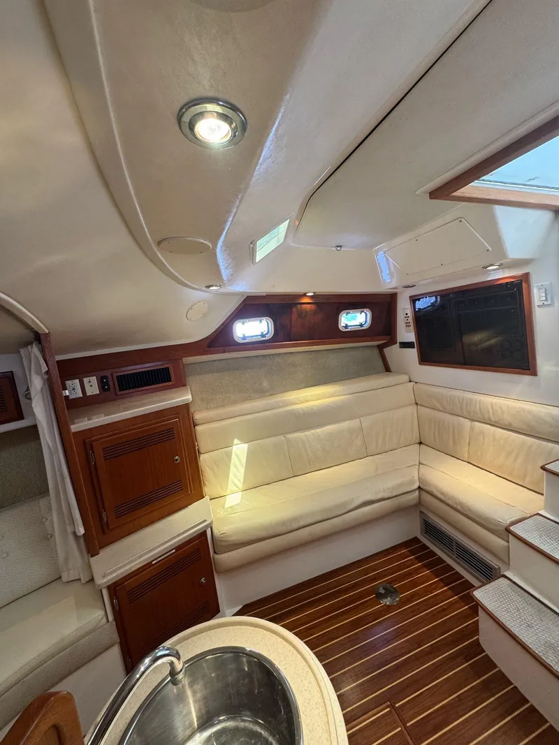 Slide: The Image of Interior of a 1998 Cabo 35 Express boat with wood flooring and beige seating. - 21