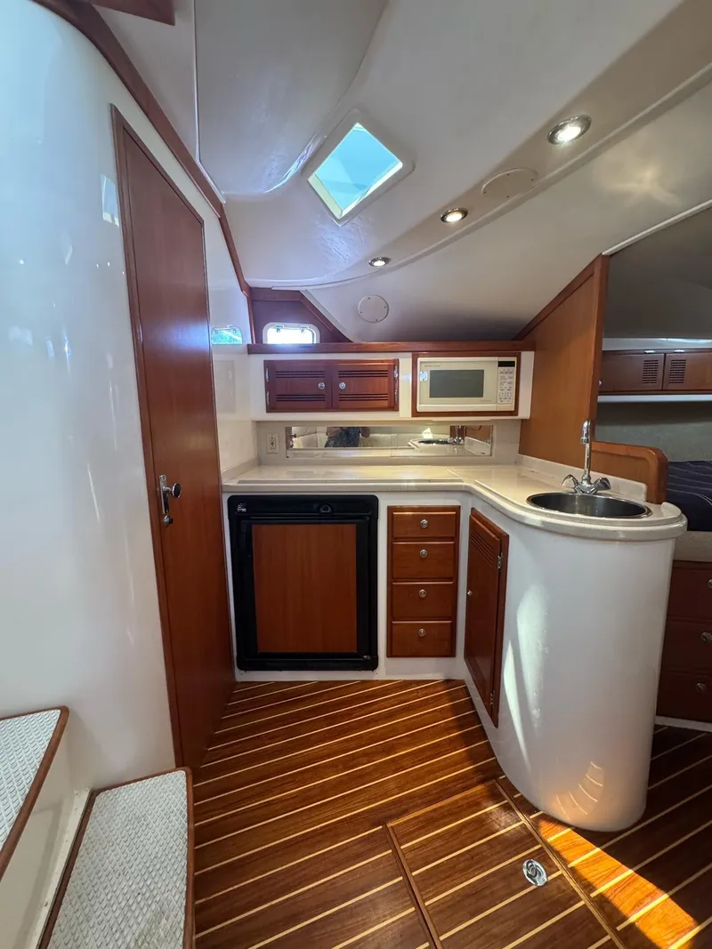 Slide: The Image of 1998 Cabo 35 Express yacht interior with kitchenette, wood cabinets, and modern appliances. - 26