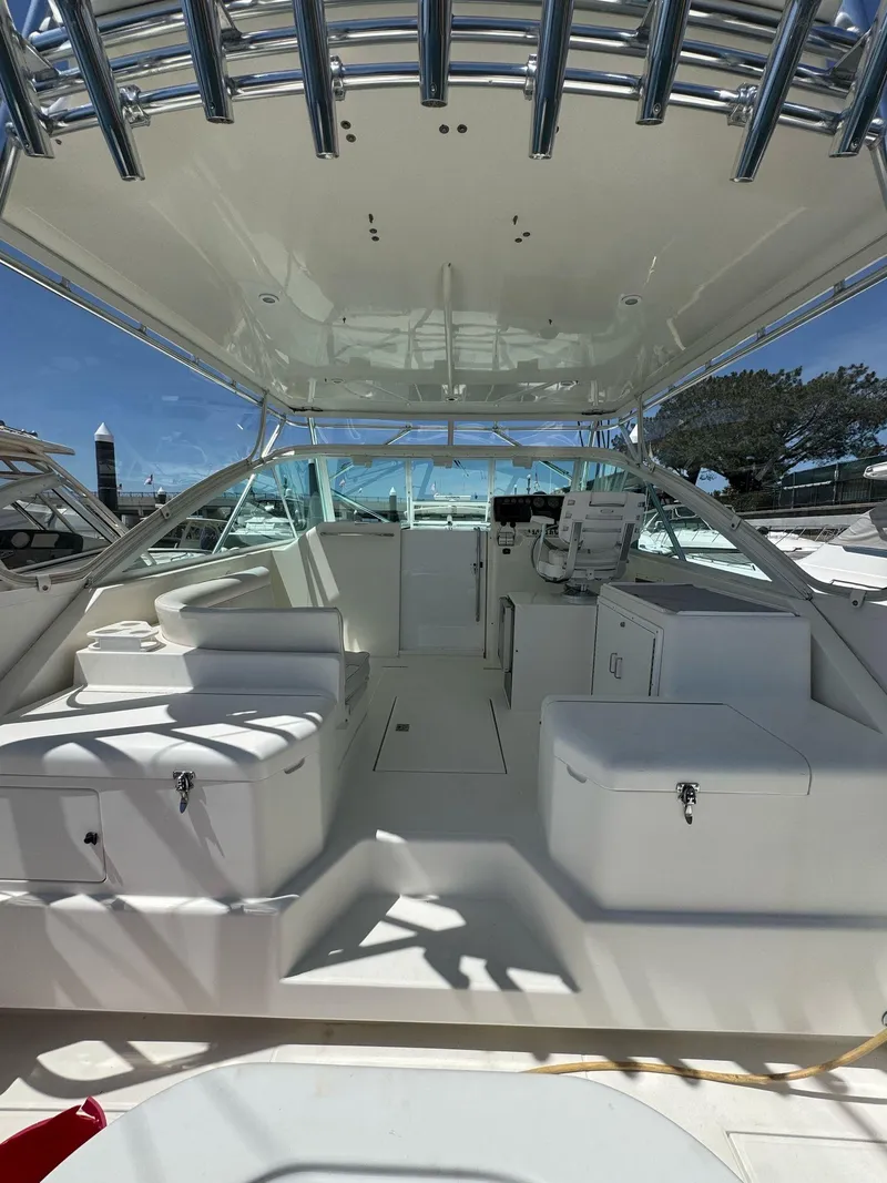 Slide: The Image of 1998 Cabo 35 Express boat interior with seating and helm, under a clear blue sky. - 33
