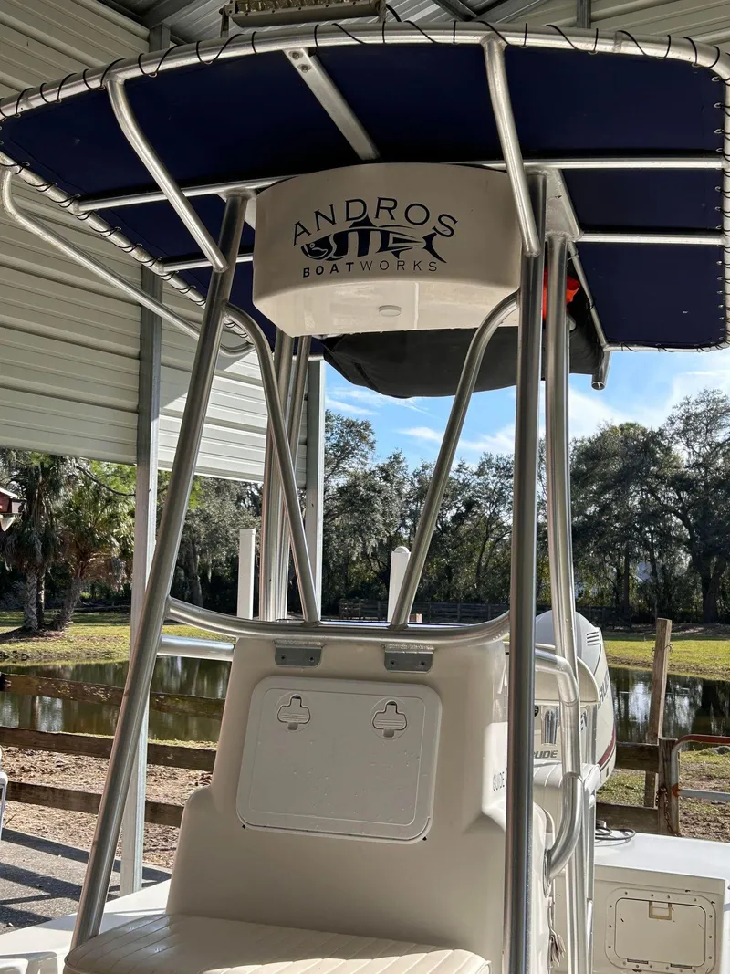 Slide: The Image of 2014 Andros Guide 20 boat with T-top, parked in a covered area near a pond. - 10