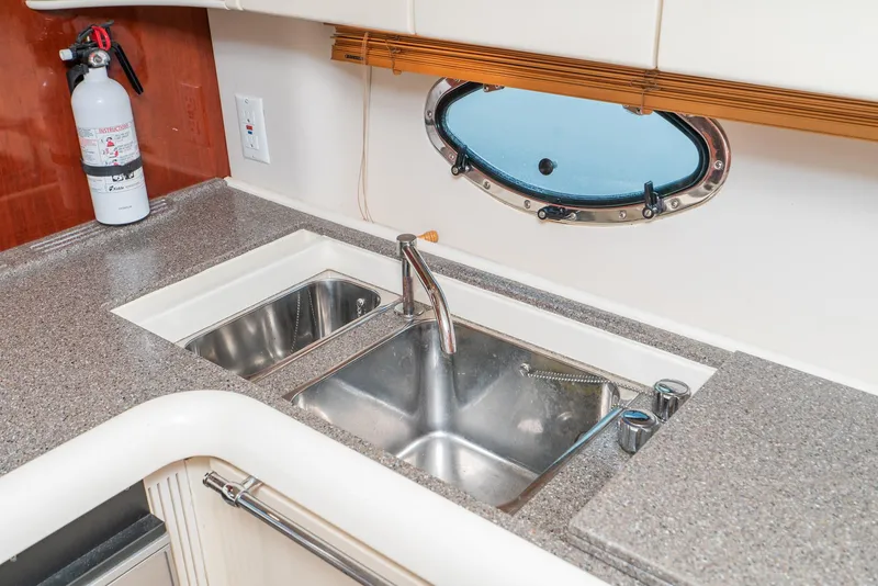 Slide: The Image of Kitchen sink area on a 2000 Fairline 48 Targa yacht with porthole and fire extinguisher. - 37
