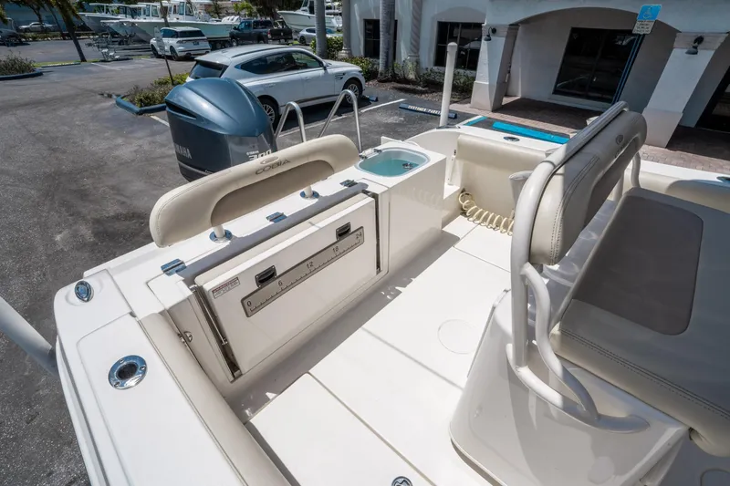 Slide: The Image of 2017 Cobia 237 CC boat interior with seating and storage, parked near vehicles. - 10