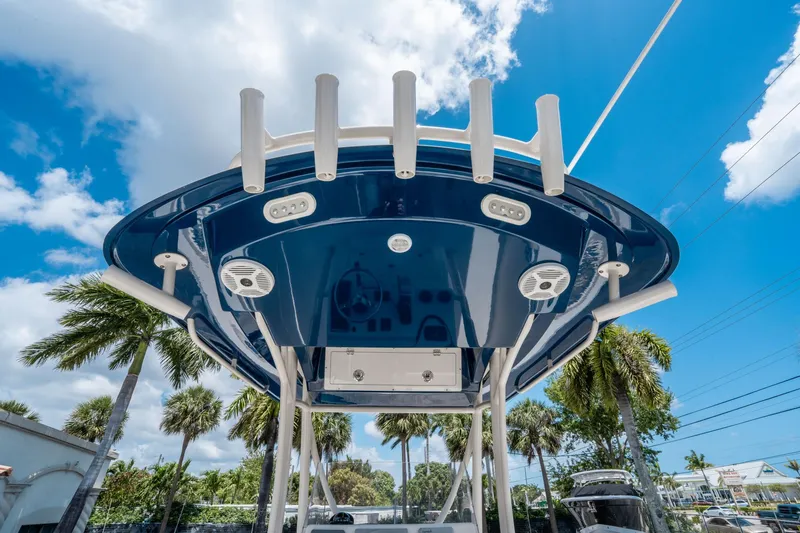 Slide: The Image of 2017 Cobia 237 CC boat with blue T-top, rod holders, and speakers under a sunny sky. - 21