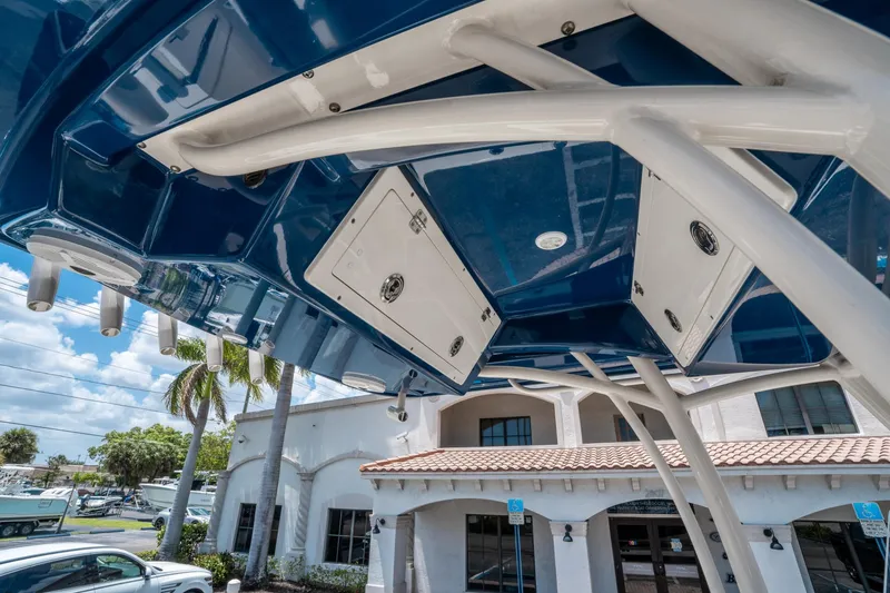 Slide: The Image of 2017 Cobia 237 CC boat's blue T-top with rod holders and storage compartments. - 22