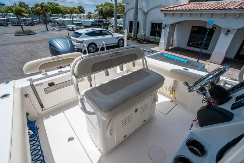 Slide: The Image of 2017 Cobia 237 CC boat interior with seating and steering wheel in a parking lot. - 24