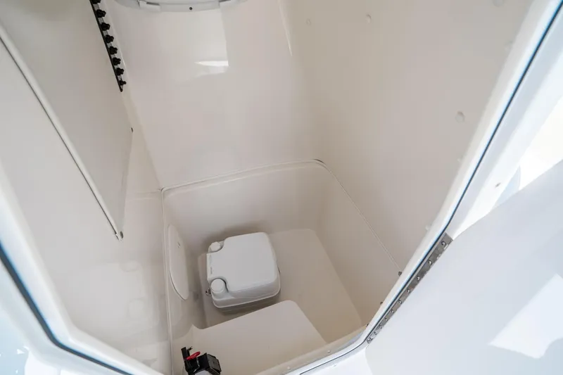 Slide: The Image of Interior of 2017 Cobia 237 CC boat, featuring a compact marine toilet. - 26