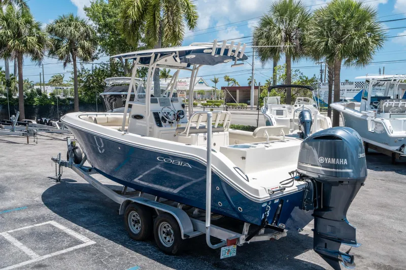 Slide: The Image of 2017 Cobia 237 CC boat with Yamaha engine on trailer, surrounded by palm trees. - 4