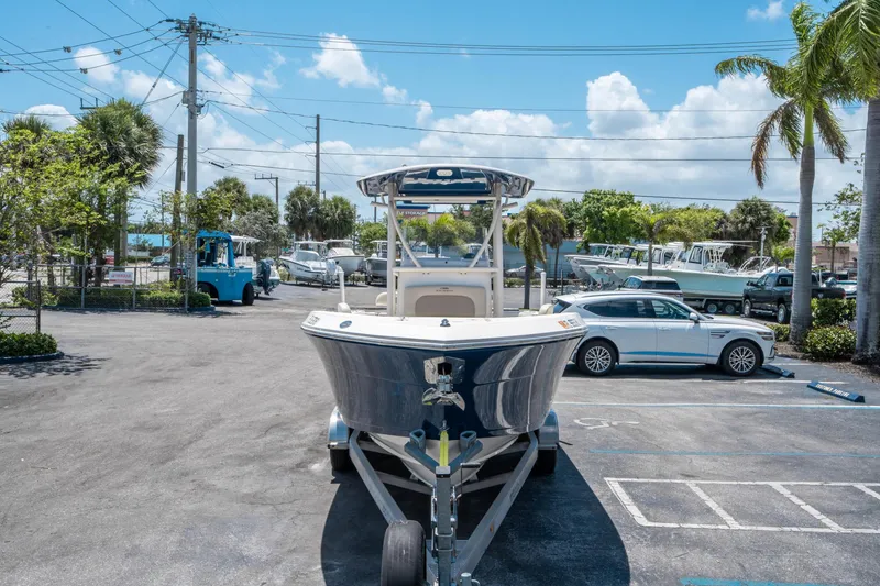 Slide: The Image of 2017 Cobia 237 CC boat on trailer in sunny parking lot with palm trees. - 7