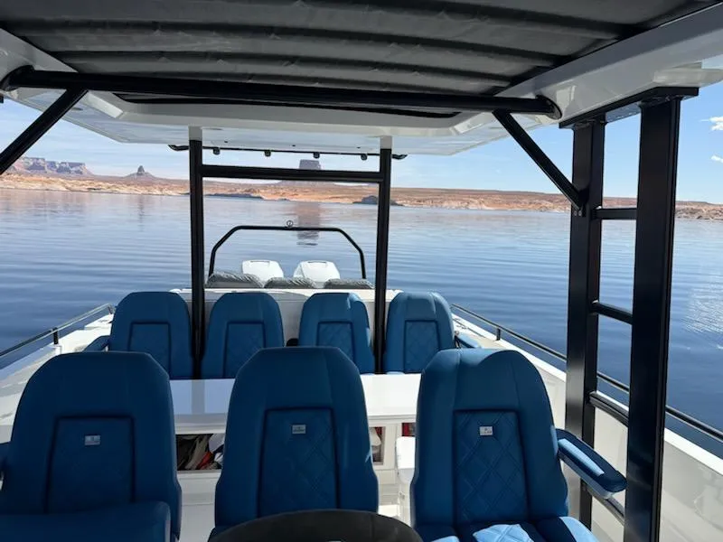 Slide: The Image of 2019 Axopar Brabus boat interior with blue seating, on a calm lake with scenic views. - 4