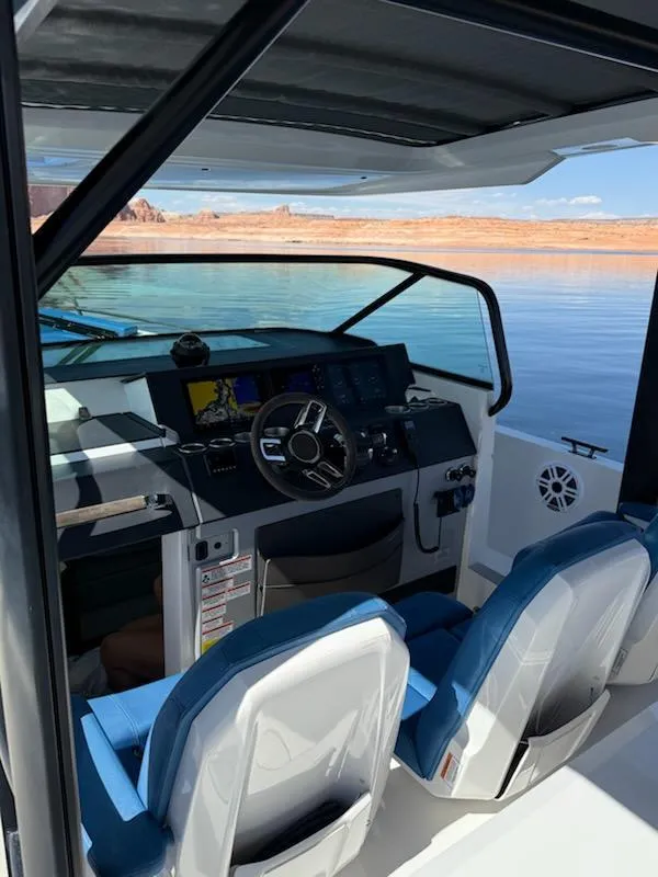 Slide: The Image of 2019 Axopar Brabus boat interior with steering wheel, blue seats, and scenic water view. - 5