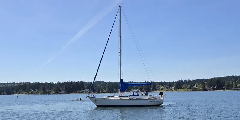 Slide: The Image of 1985 Pearson 385 sailboat on calm water with forested shoreline in the background. - 0