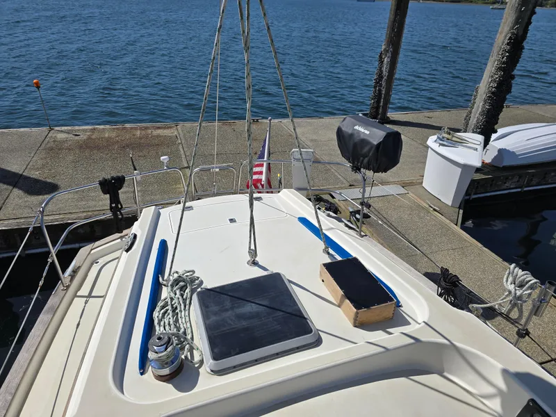Slide: The Image of 1985 Pearson 385 sailboat docked, featuring deck equipment and ropes, with a scenic waterfront view. - 10