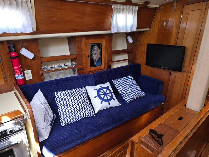 Slide: The Image of Cozy 1985 Pearson 385 sailboat interior with blue sofa, nautical pillows, and wooden decor. - 16
