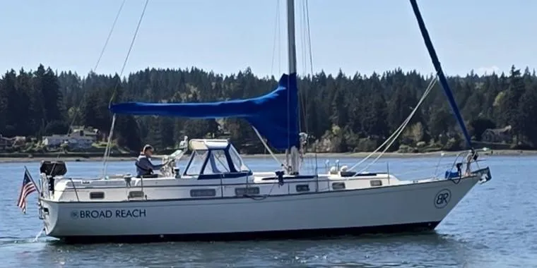 Slide: The Image of 1985 Pearson 385 sailboat "Broad Reach" on calm water with forested shoreline. - 2