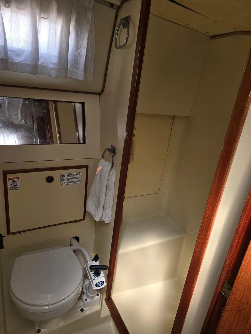 Slide: The Image of 1985 Pearson 385 yacht bathroom with toilet, mirror, and storage shelves. - 21