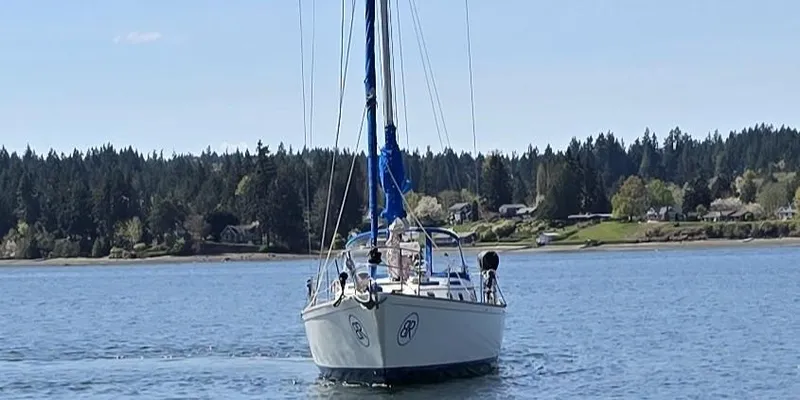 Slide: The Image of 1985 Pearson 385 sailboat on calm water with forested shoreline in the background. - 3
