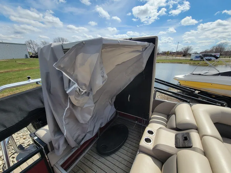 Slide: The Image of 2021 Landau 220 Atlantis boat interior with seating and canopy, docked by a lake. - 22