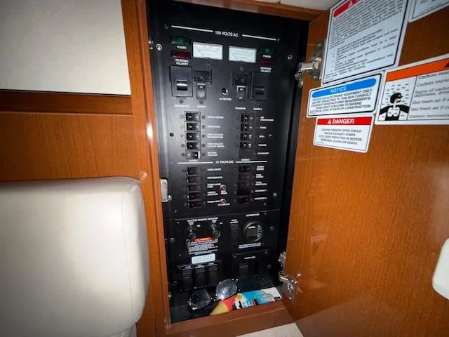 Slide: The Image of Electrical panel inside 2009 Sea Ray 350 Sundancer boat, featuring various switches and safety labels. - 15
