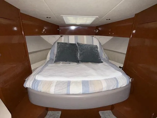 Slide: The Image of 2009 Sea Ray 350 Sundancer cabin with cozy bed and wooden interior. - 18