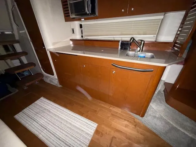 Slide: The Image of Interior of 2009 Sea Ray 350 Sundancer yacht, featuring a modern kitchenette with wood cabinetry. - 23