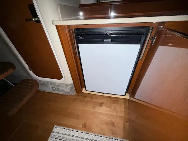 Slide: The Image of 2009 Sea Ray 350 Sundancer interior with built-in refrigerator and wooden cabinetry. - 25