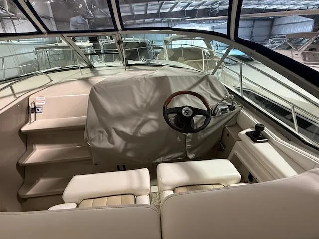 Slide: The Image of 2009 Sea Ray 350 Sundancer helm with covered controls in a marina setting. - 6