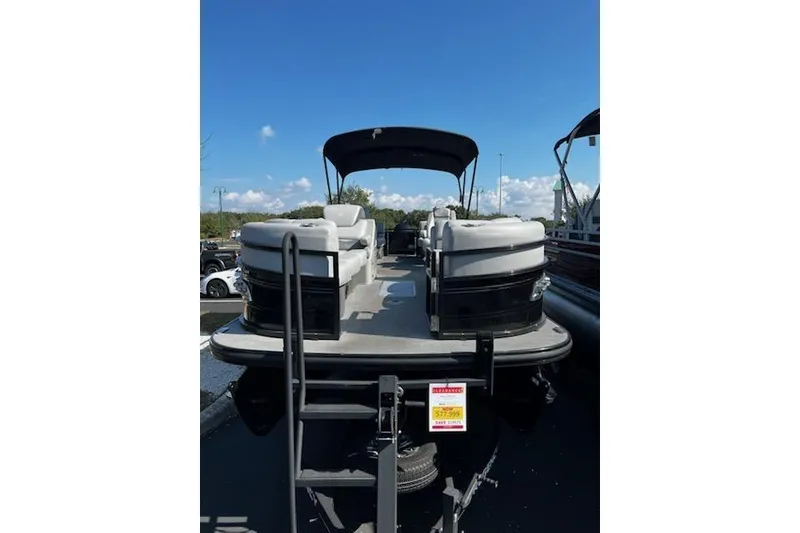 Slide: The Image of 2024 Regency 250 LE3 pontoon boat with canopy, parked outdoors under a clear blue sky. - 2